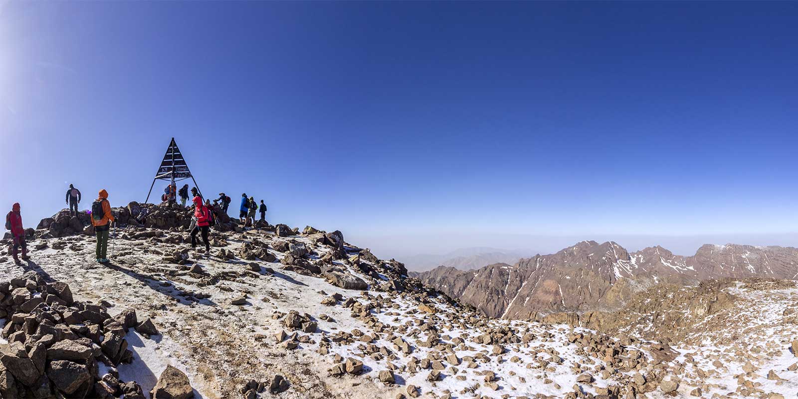 Trekkers at Mount Toubkal snow-covered summit with mountain scenery