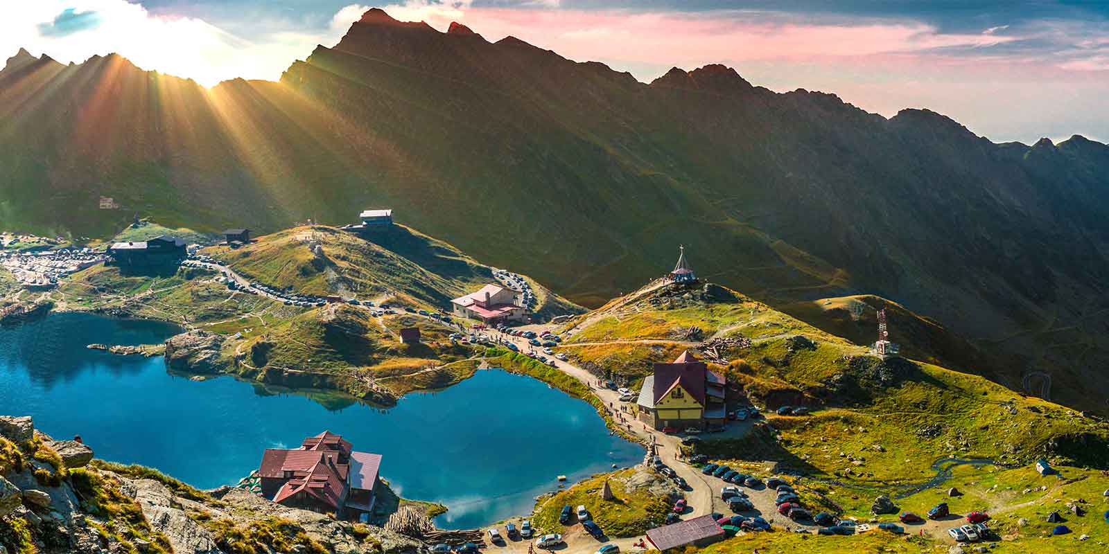 Balea Lake and cottages in valley surrounded by Fagaras mountains