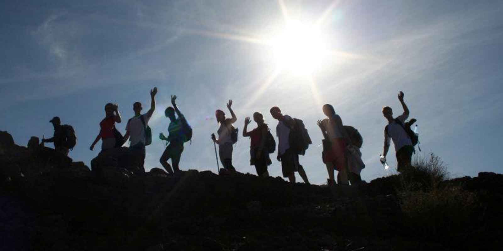 School group trekking with bright sun in background