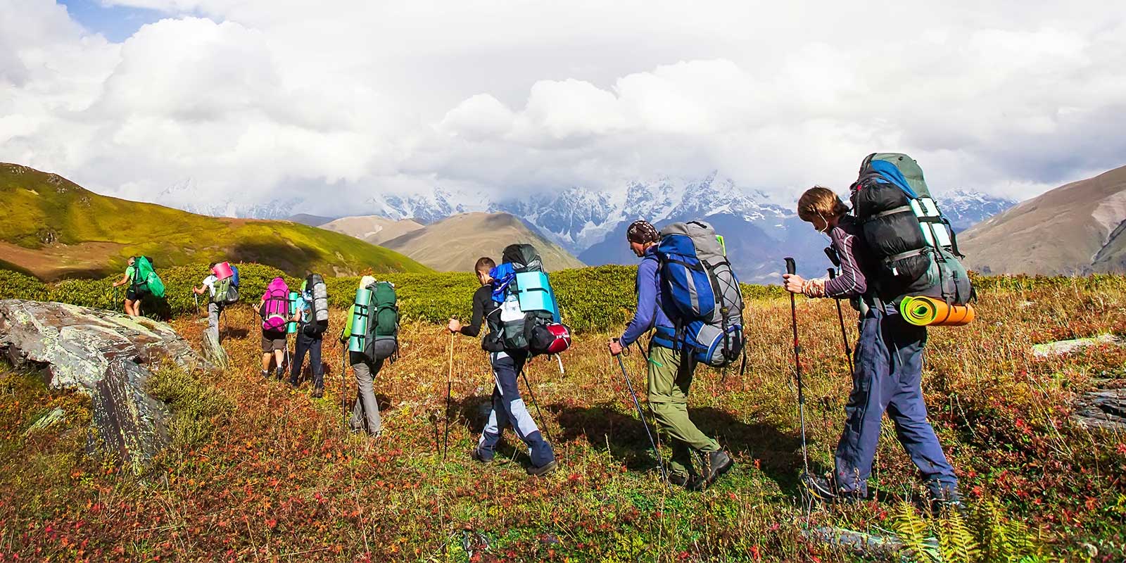 Group trekking with camping gear in mountains