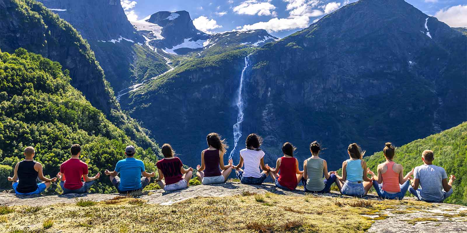 Group of young people sitting in a row holding hands on a mountain