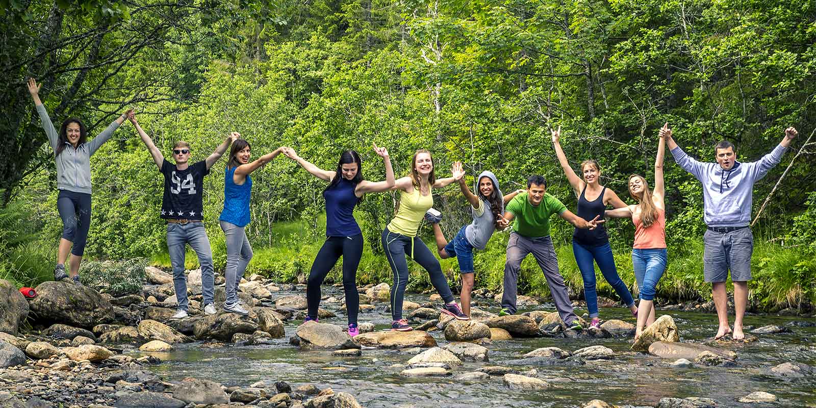 Group of happy young people with hands in the air in a stream