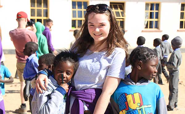 British school girl with local children in Namibia school on school group visit