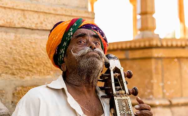 Sadhu holyman playing an instrument outside temple in India
