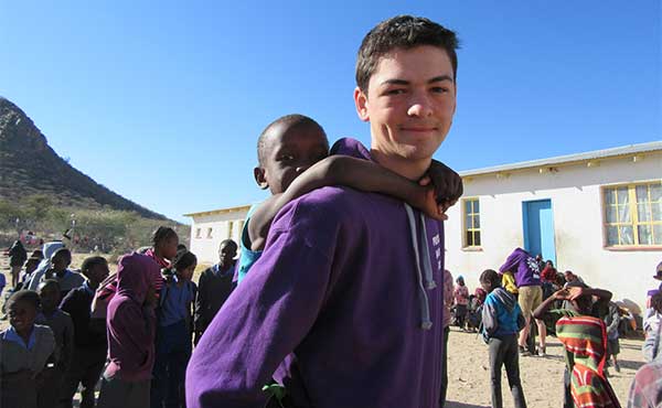 Student with young pupil on his shoulders at a school in Namibia