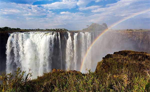 A rainbow in the foreground with Victoria Falls in the background