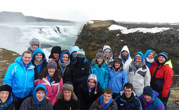School group in front of a huge cascading waterfall in Iceland