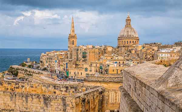 View of buildings in Malta's capital city of Valetta, with the Mediterranean sea in the background