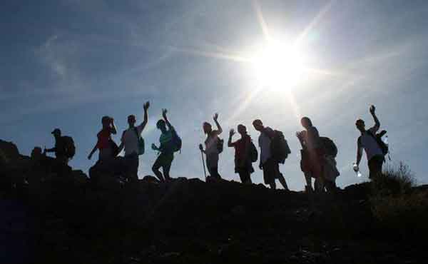 School group trekking with bright sun in background